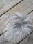 A fluffy silver-gray faux fur pom-pom on a wooden surface as part of sheepskin sample squares
