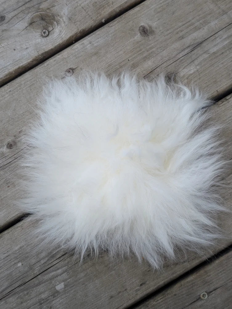 A fluffy white sheepskin pom pom from sheepskin sample squares perfect for soft cozy accents
