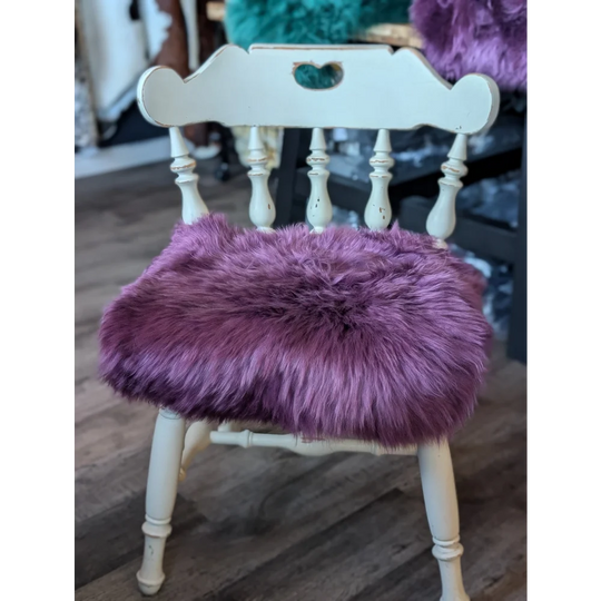 Plum purple merino sheepskin chair pad on white wooden frame