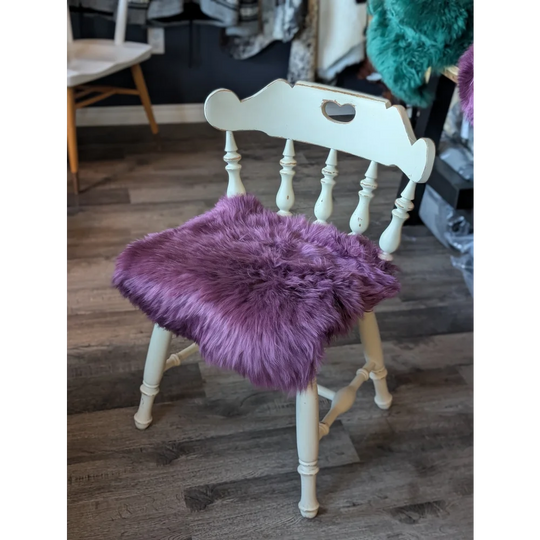 Plum purple merino sheepskin chair pad with lavender faux fur on white wooden spindle frame