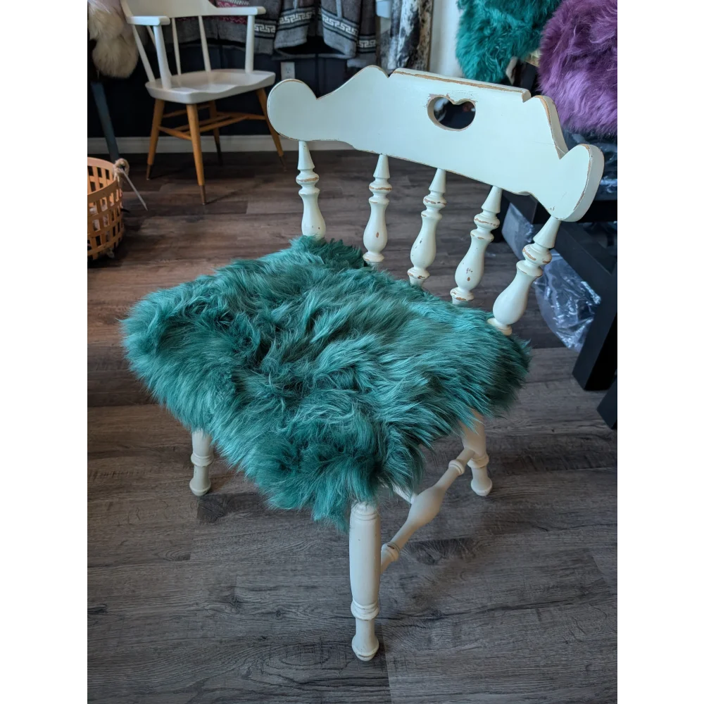 White wooden chair with teal fur cushion and gorgeous green merino sheepskin pad