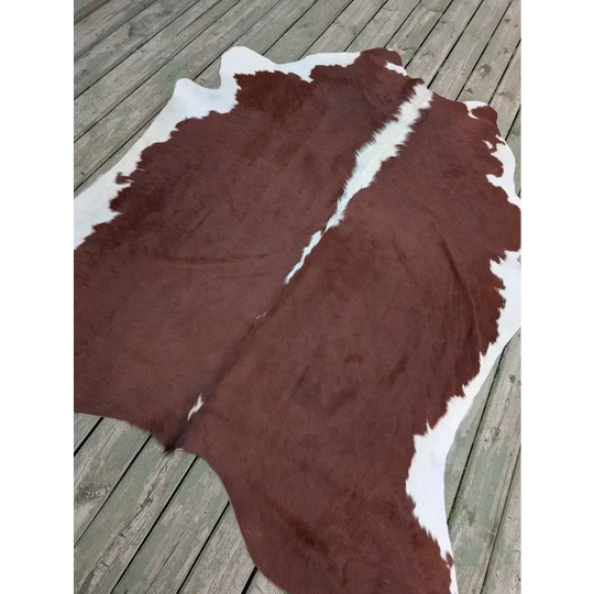 Large 85’’ x 74.5’’ cowhide rug with brown and white patches, leather texture