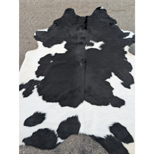 Large cowhide rug with black and white patches and natural leather texture