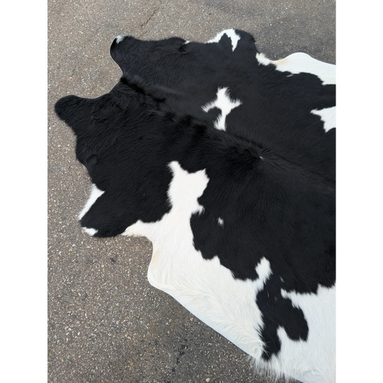 Large cowhide rug with black and white patches and natural leather texture