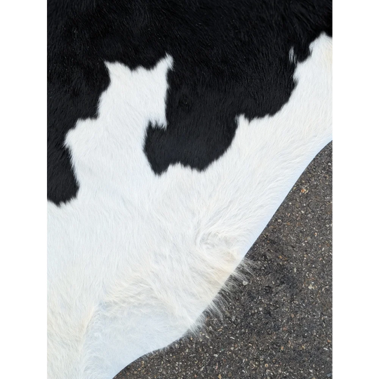 Large cowhide rug with black and white patches and textured surface for stylish decor