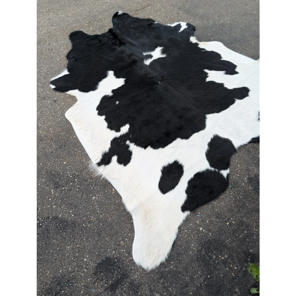 Large cowhide rug with black and white spots and natural leather texture