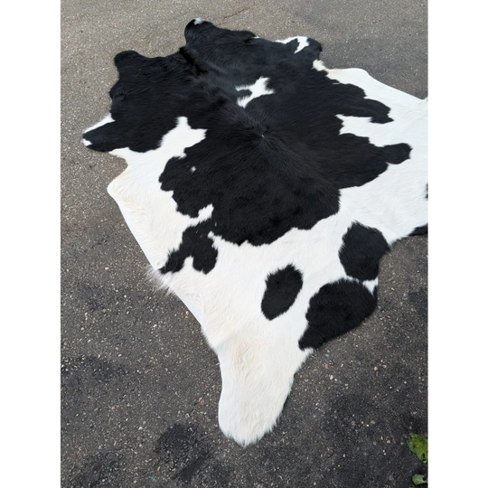 Large cowhide rug with black and white spots and natural leather texture