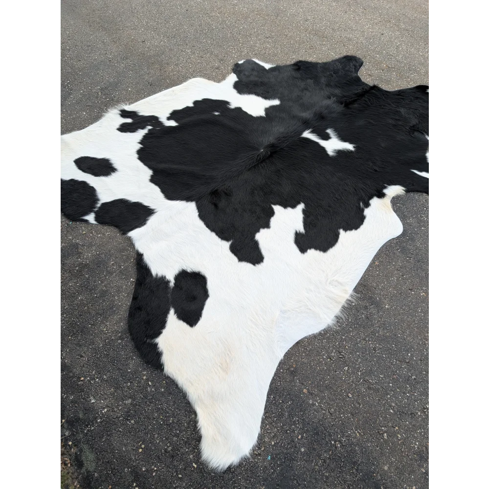 Large cowhide rug with black and white spots and natural leather texture