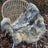 A soft, naturally dyed gray and cream-colored sheepskin rug with a fluffy texture.