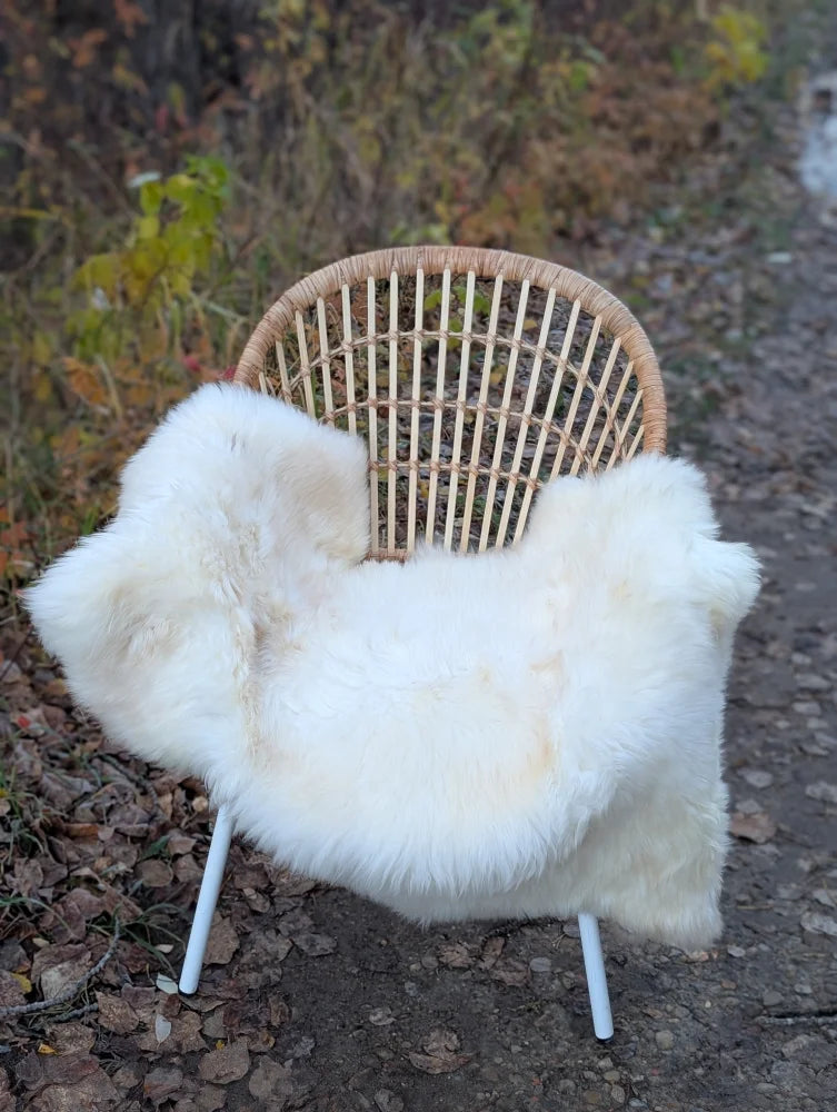 White british isles sheepskin throw draped over wicker chair with white metal legs soft and cozy design