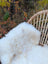 White fluffy british isles sheepskin throw draped over a woven wicker chair softbrit 45.5 x 30 inches
