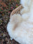 A softbrit#1 british isles sheepskin plush off-white blanket draped over a woven wicker chair