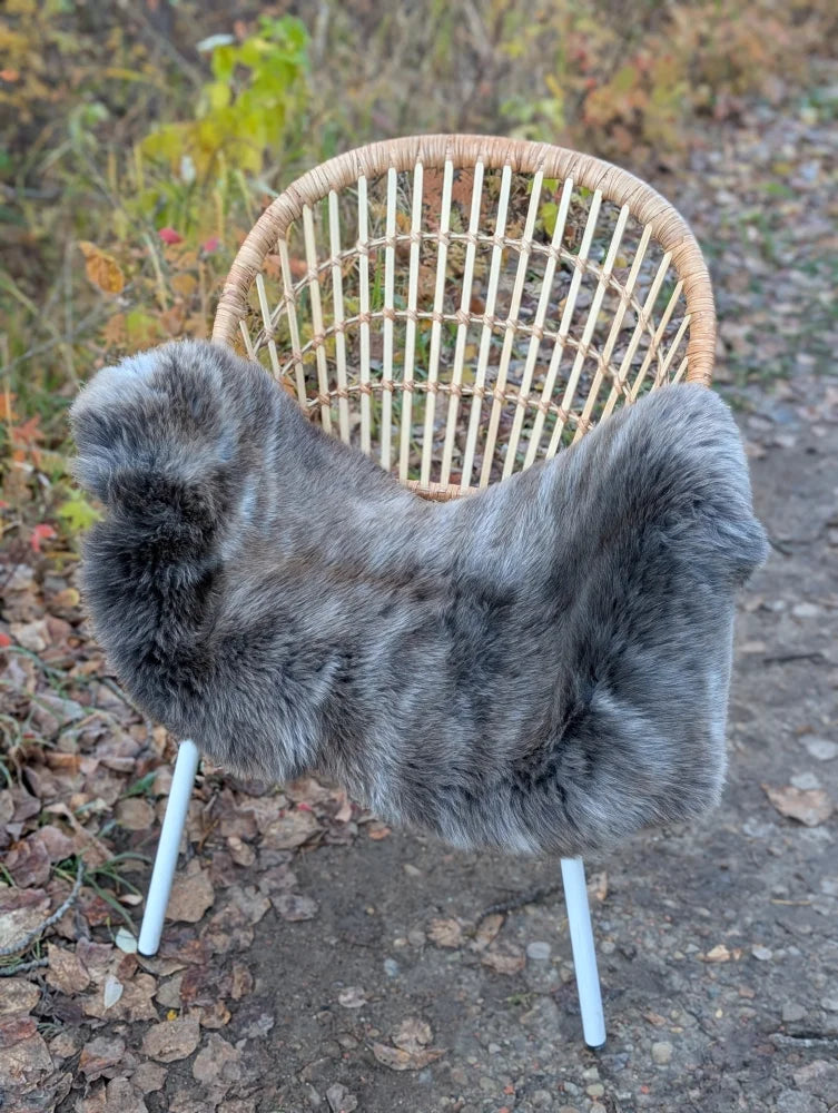 Gray faux fur chair cover draped over woven rattan chair with white metal legs softbrit 2 british isles sheepskin