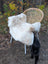 A cream-colored plush british isles sheepskin blanket draped over a wicker chair soft and cozy
