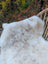 A soft fluffy white and beige british isles sheepskin throw resting on a woven wicker chair