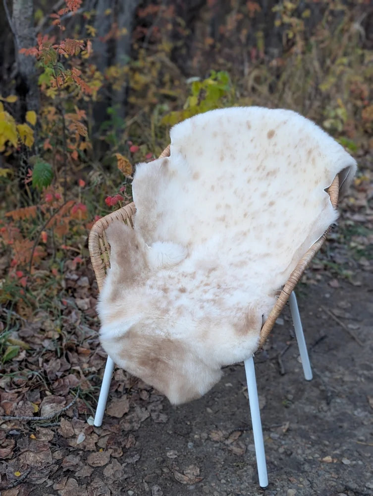 Softbrit3 cream british isles sheepskin rug with brown speckles draped over a woven wicker chair