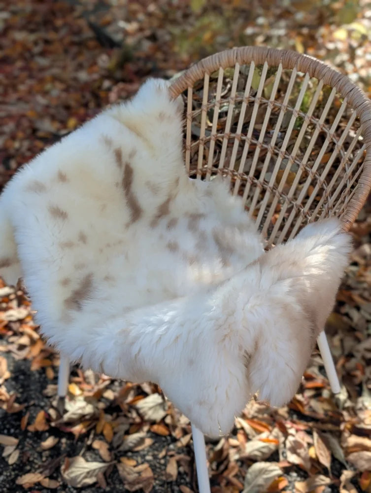 Softbrit4 white faux fur throw with brown speckles draped on wicker chair soft british isles sheepskin