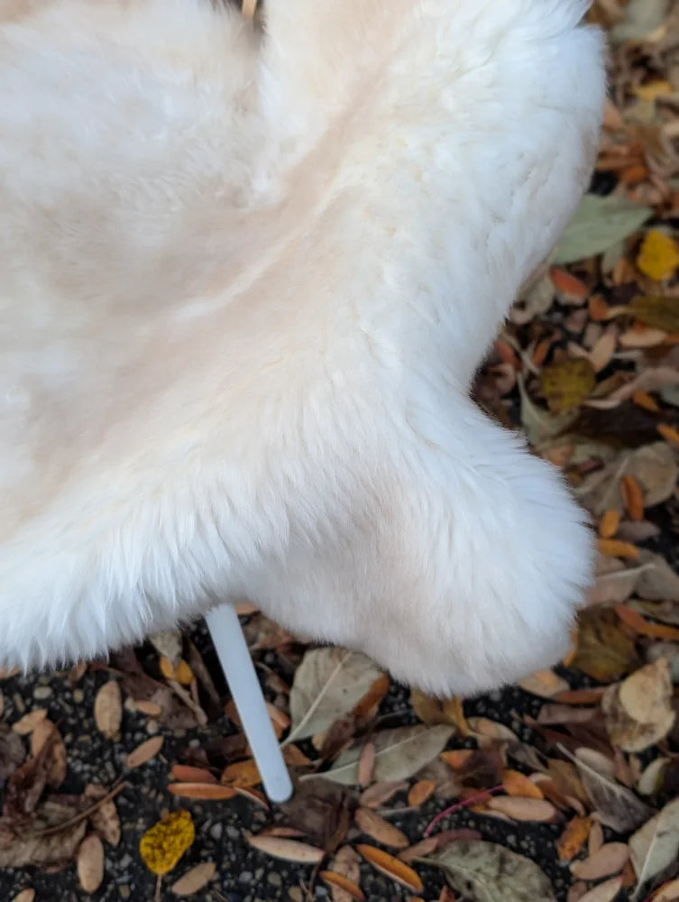 A plush white fluffy dog toy made from very soft british isles sheepskin with a rounded shape and soft texture