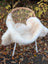 A softbrit5 46 x 29 off-white very soft british isles sheepskin faux fur throw on a wicker chair with white metal legs
