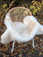 A softbrit#5 off-white plush faux fur british isles sheepskin throw draped on a wicker chair with white metal legs