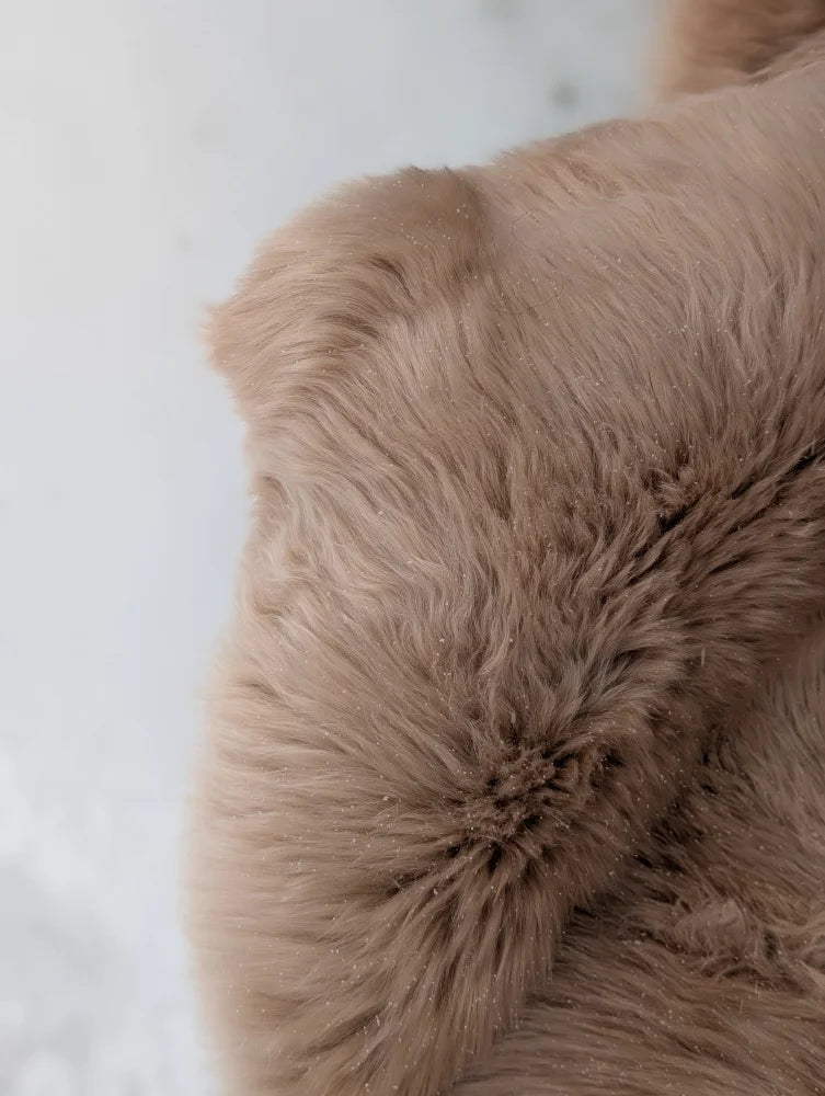 A plush light taupe merino sheepskin throw with dense soft texture and subtle shades perfect for mid october cozy vibes