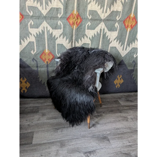Black Icelandic sheepskin rug draped over white wooden chair