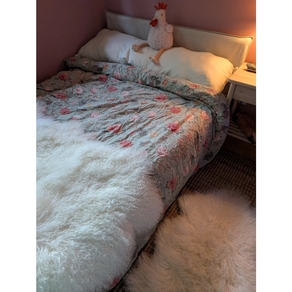 Gorgeous Angus Oliver Mongolian sheepskin duvet with floral pattern, white fur throw, and chicken plush toy