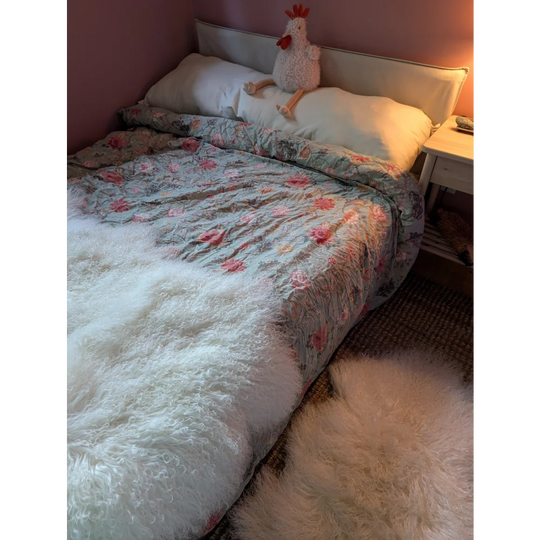 Gorgeous Angus Oliver Mongolian sheepskin duvet with floral pattern, white fur throw, and chicken plush toy