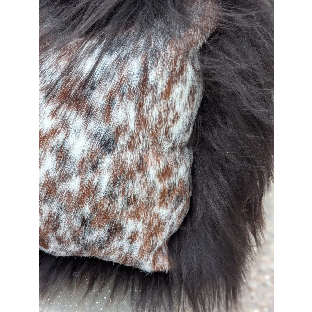 A speckled cowhide plush pillow with browny black natural cowhide and long wool texture for cozy decor
