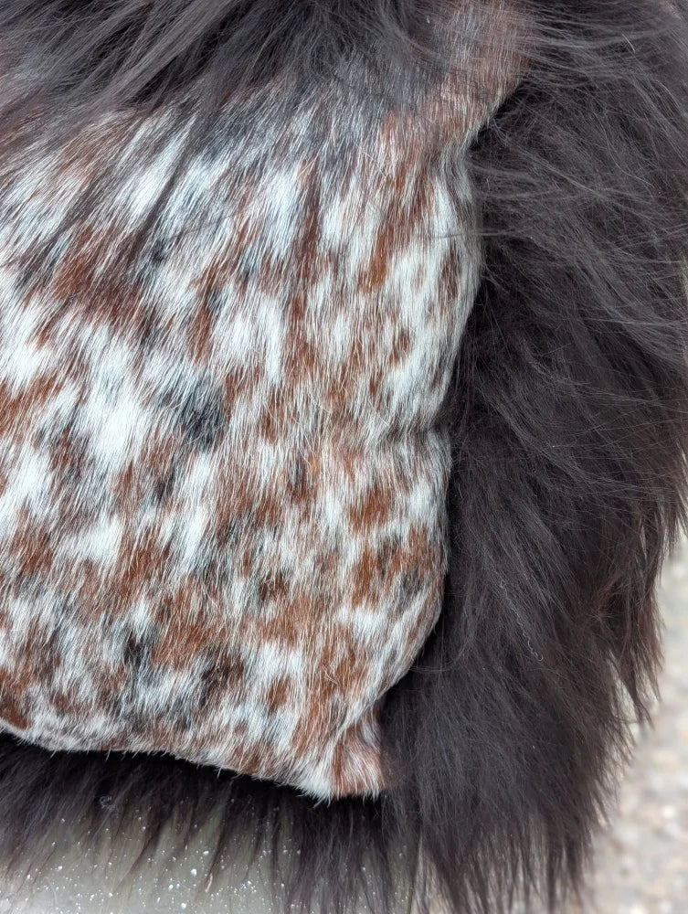 A speckled cowhide plush pillow with browny black natural cowhide and long wool texture for cozy decor