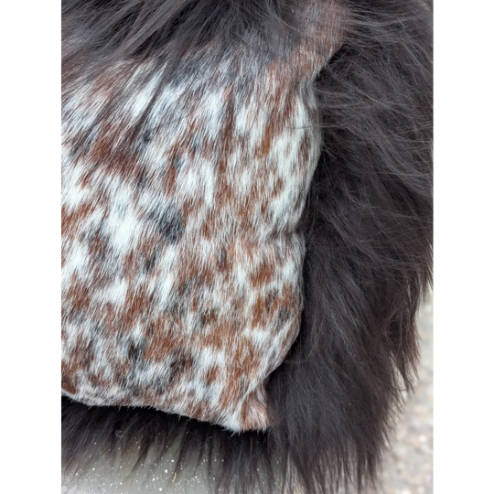 A speckled cowhide plush pillow with browny black natural cowhide and long wool texture for cozy decor