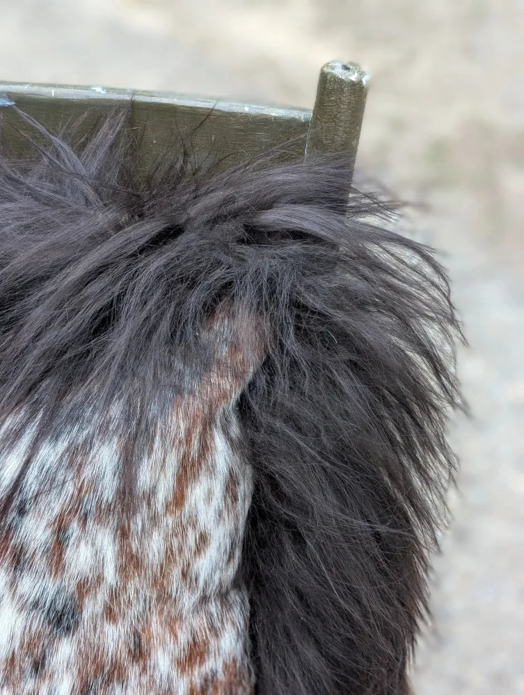 Black faux fur trim on the shoulder of a speckled cowhide and browny black icelandic knit with long wool details