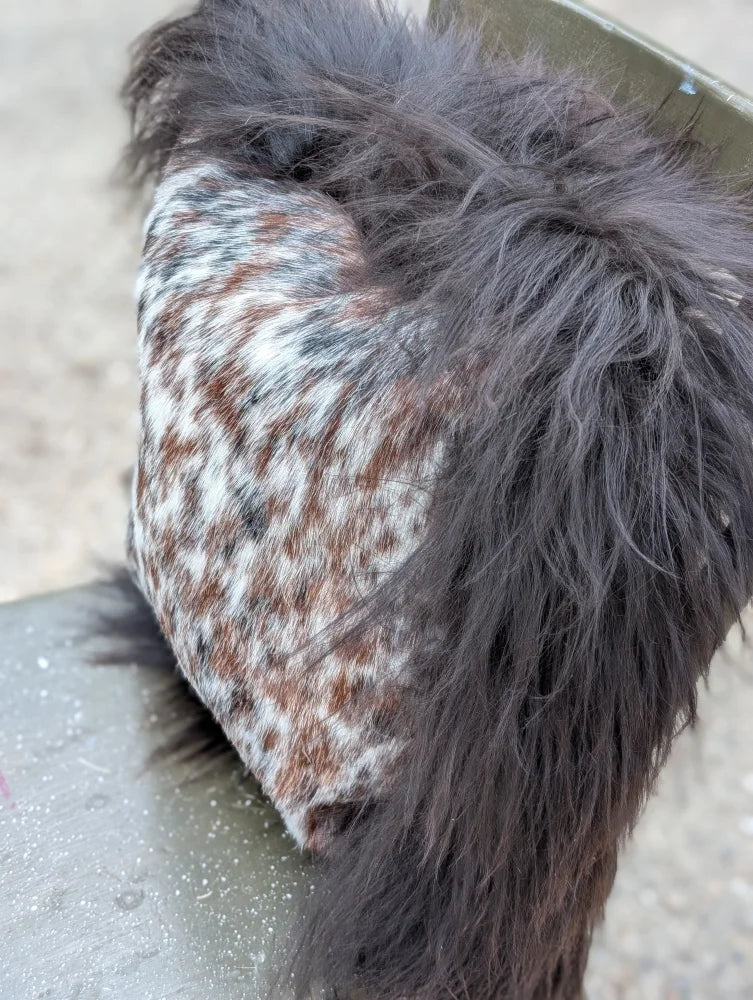 A plush speckled cowhide bootie with dark brown and white long wool fur lined for cozy comfort
