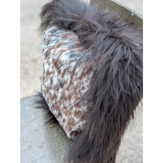 A plush speckled cowhide bootie with dark brown and white long wool fur lined for cozy comfort