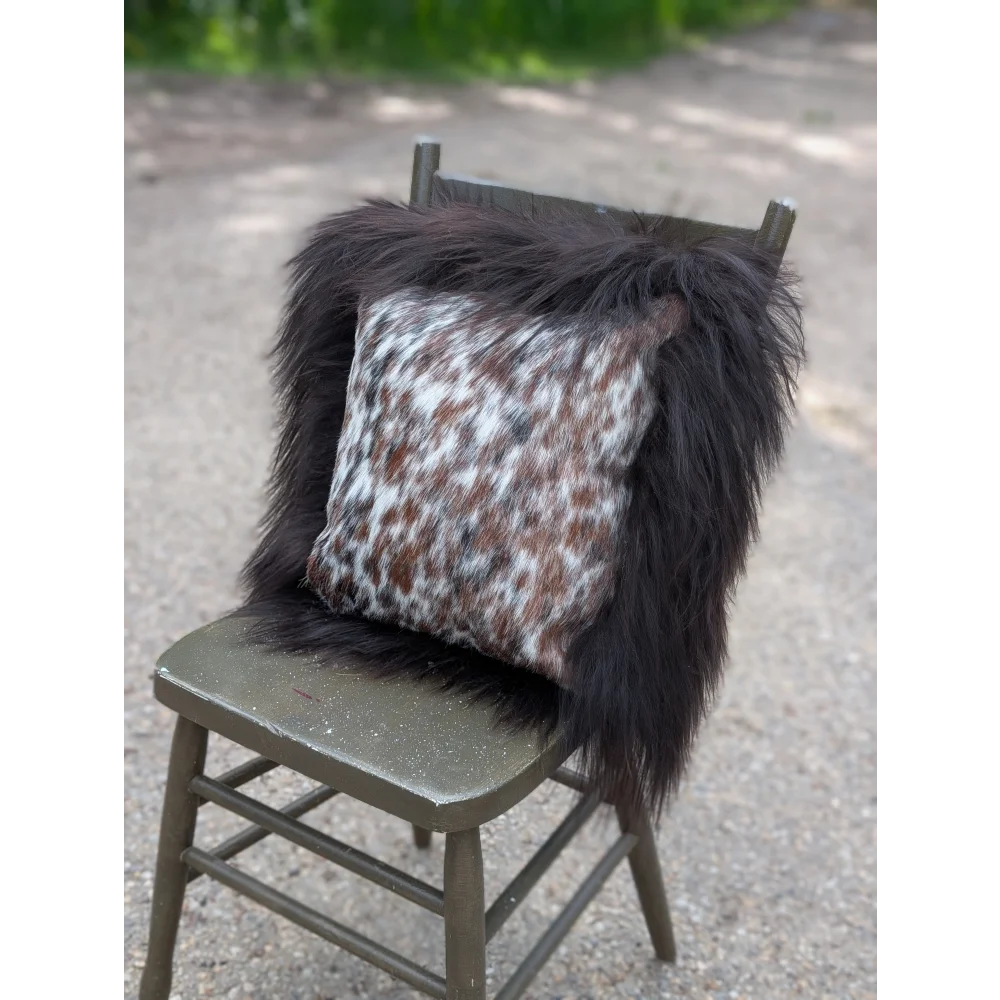 Faux fur throw pillow with white brown and black spotted pattern inspired by natural cowhide and long wool textures