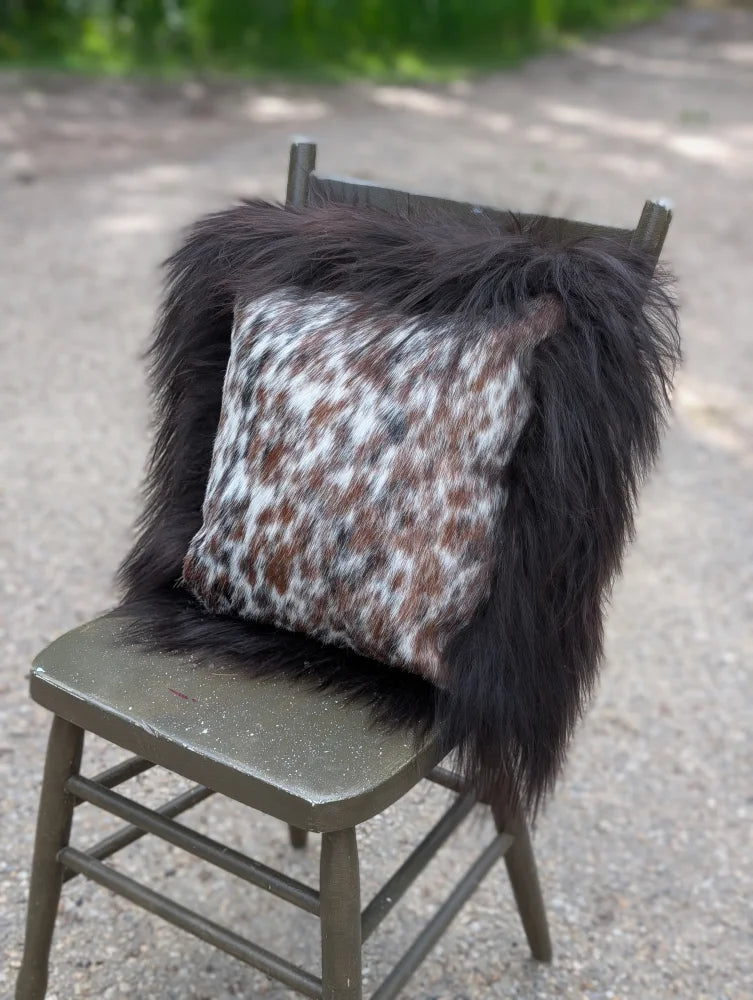 Faux fur throw pillow with white brown and black spotted pattern inspired by natural cowhide and long wool textures