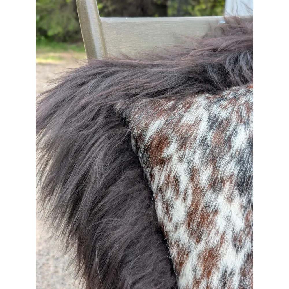 A plush speckled cowhide and browny black icelandic cushion with natural cowhide and soft long wool texture