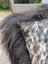 A plush speckled cowhide and browny black icelandic cushion with natural cowhide and soft long wool texture