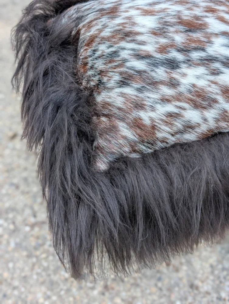 A plush dark gray faux fur trim with a speckled natural cowhide patch on the speckled cowhide and browny black icelandic