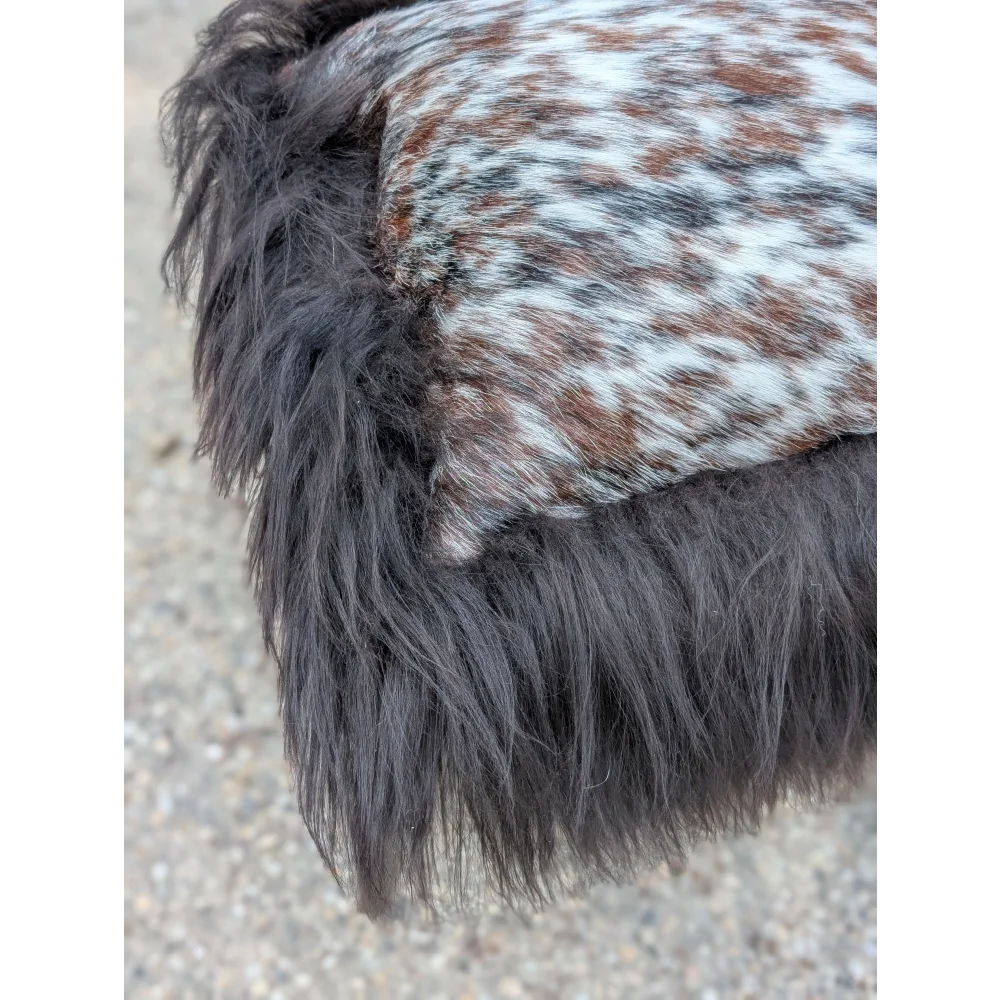 A plush dark gray faux fur trim with a speckled natural cowhide patch on the speckled cowhide and browny black icelandic