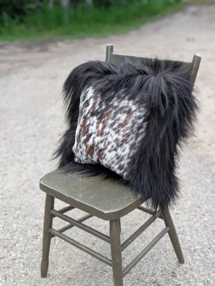 Black and white speckled natural cowhide pillow with long wool black shaggy trim perfect for sewing machines decor