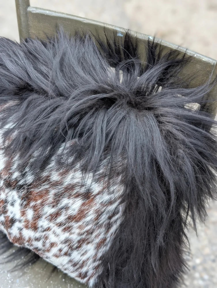 A speckled cowhide boot with a natural black icelandic long wool pom-pom on top for cozy style