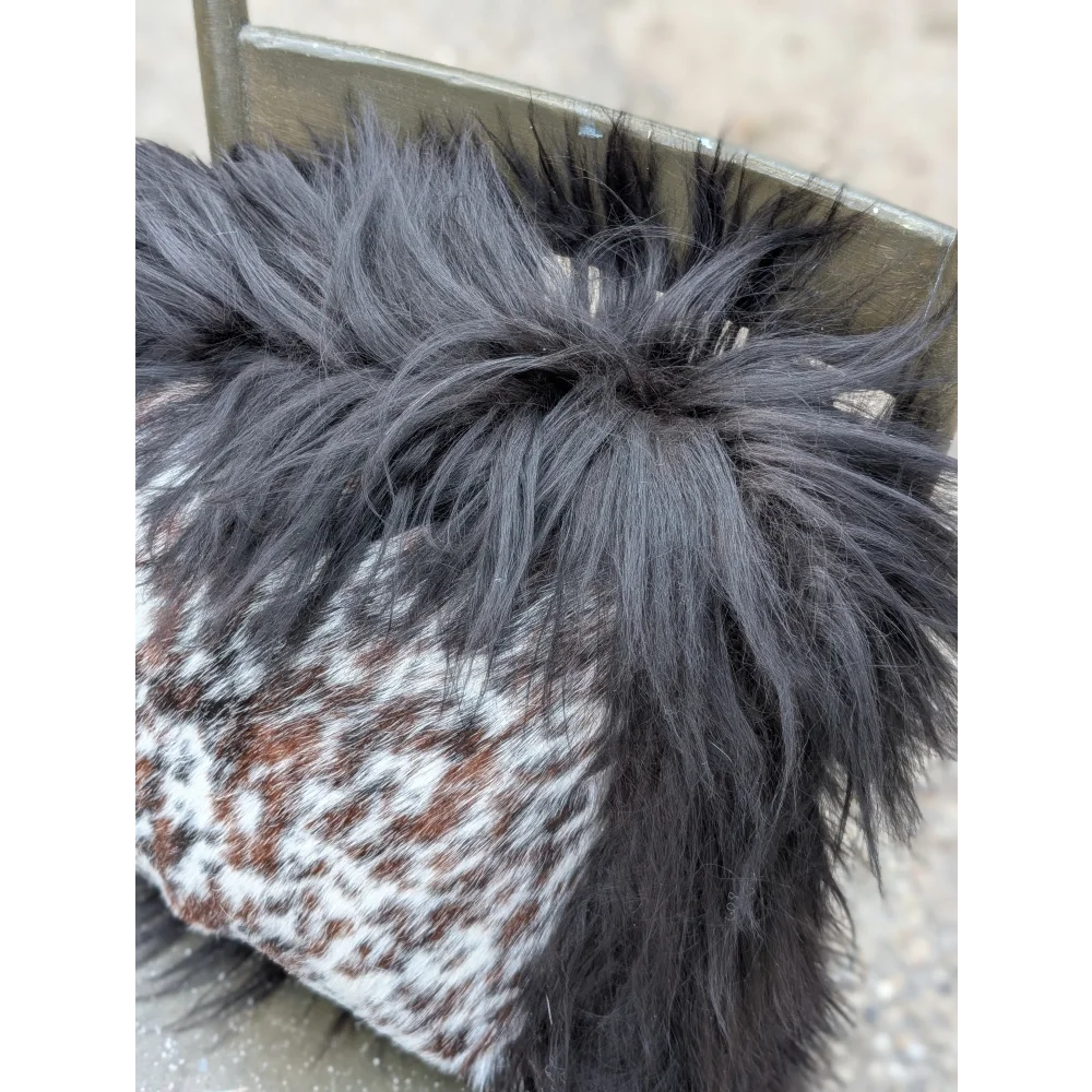 A speckled cowhide boot with a natural black icelandic long wool pom-pom on top for cozy style