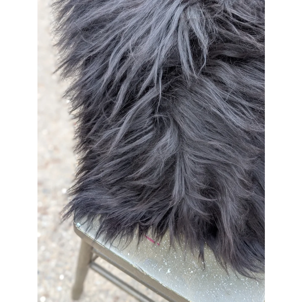 A plush dark gray faux fur blanket with long wool strands inspired by natural cowhide for cozy comfort