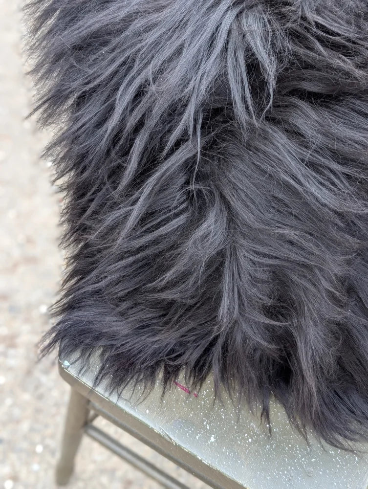 A plush dark gray faux fur blanket with long wool strands inspired by natural cowhide for cozy comfort