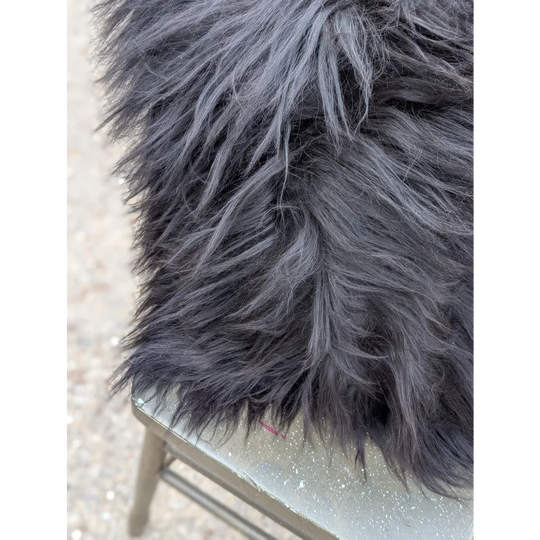 A plush dark gray faux fur blanket with long wool strands inspired by natural cowhide for cozy comfort