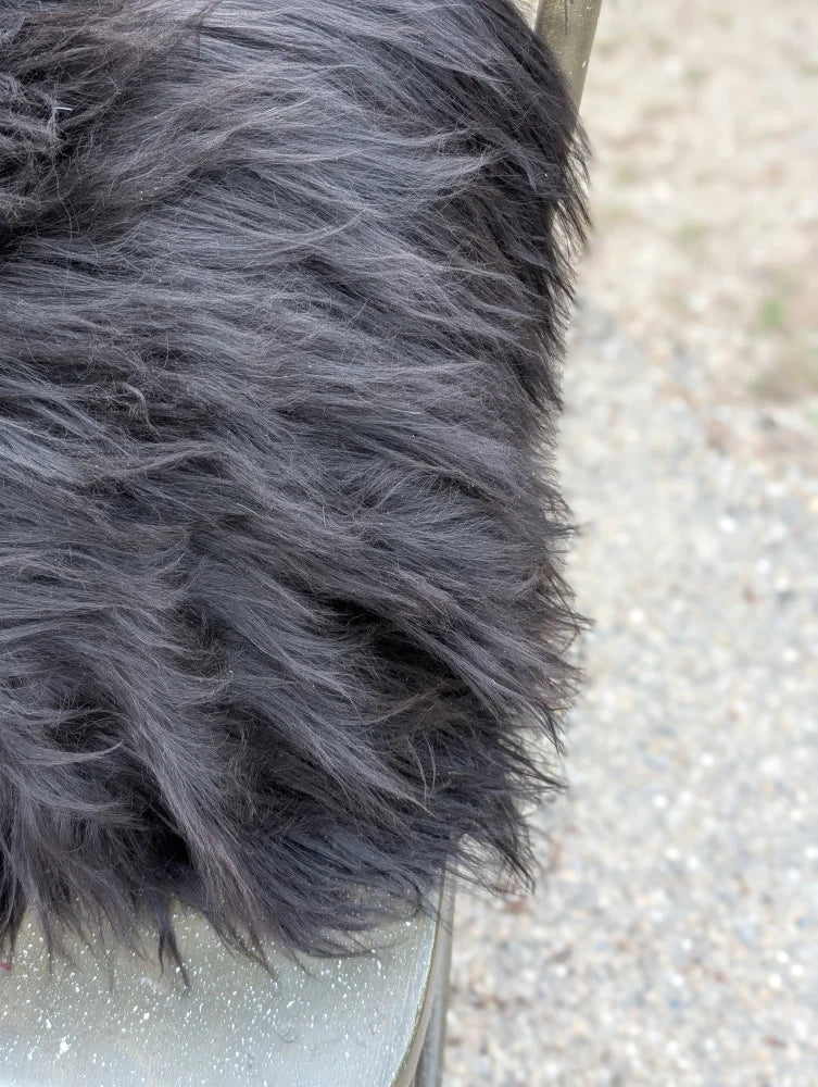 A thick dark gray faux fur blanket with soft plush texture inspired by natural cowhide and long wool design