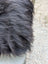 A thick dark gray faux fur blanket with soft plush texture inspired by natural cowhide and long wool design