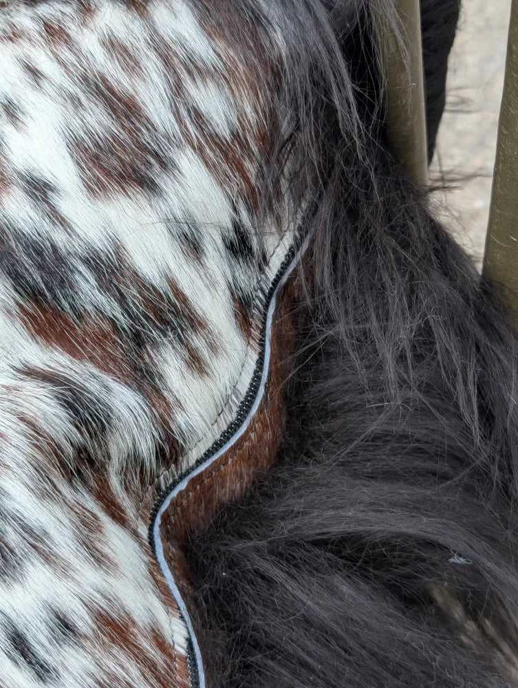 Brown and white spotted natural cowhide saddle pad with stitched edge perfect for long wool Icelandic riding