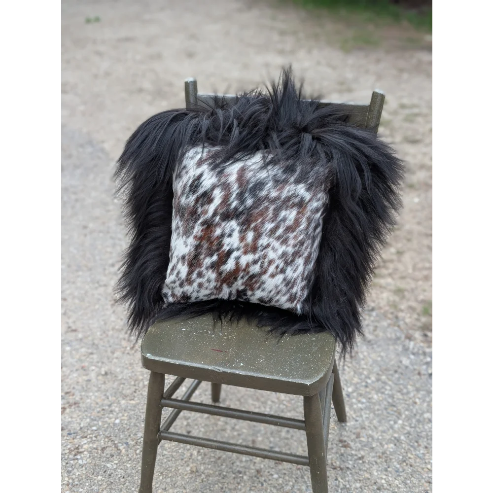 Black and white natural cowhide pillow with fluffy black long wool trim from speckled cowhide and natural black icelandic